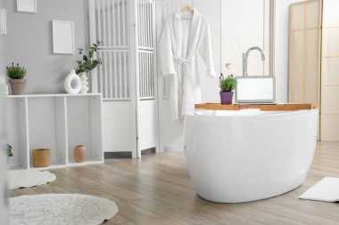 Lavanta çiçekleri ve dizüstü bilgisayarla modern banyoda küvette dikil.