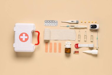 İlk yardım çantası, tıbbi malzemeler ve bej arka planda haplar.