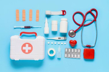İlk yardım çantasıyla kompozisyon, tıbbi malzeme ve mavi arka planda haplar