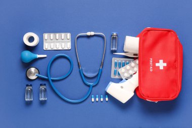 Mavi arka planda ilk yardım çantası ve tıbbi malzemeler.