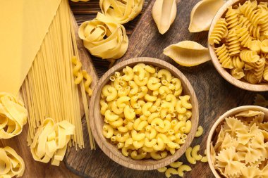 Ahşap arka planda farklı tipte makarna kaseleri, yakın plan.