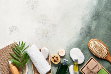 Kozmetik ürünleri şişeleri, banyo aksesuarları ve yeşil grunge arka planda spa taşlarıyla kompozisyon