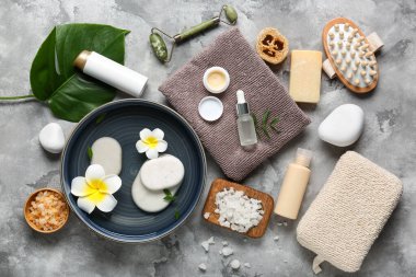 Gri grunge arka planda kozmetik ürünleri, plaka ve spa taşları içeren kompozisyon