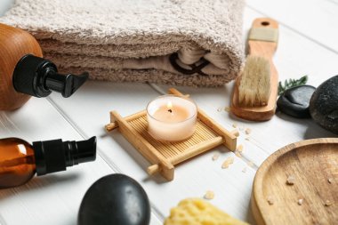 Spa taşlı kompozisyon, banyo aksesuarları ve beyaz ahşap arka planda mum, yakın plan.