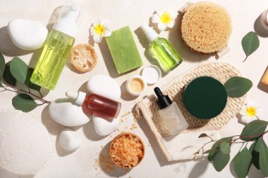 Bej grunge arka planda kozmetik ürünleri, spa taşları ve deniz tuzu içeren kompozisyon, yakın plan.