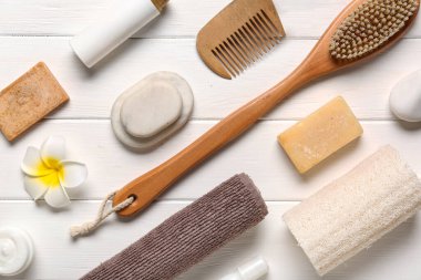 Beyaz ahşap arka planda spa taşları ve banyo aksesuarları olan kompozisyon, yakın plan.