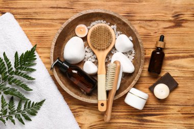 Spa taşları, kozmetik ürünler ve ahşap arka planda banyo aksesuarları olan kompozisyon