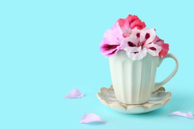 Mavi arka planda farklı güzel, yenilebilir çiçekler ve taç yaprakları olan bir fincan.