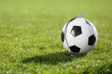 Futbol topu ve ıslık yeşil stadyum çimlerinde