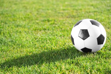 Yeşil stadyum çimlerinde futbol topu, yakın plan.