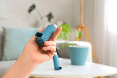 Oturma odasında modern astım spreyini tutan kadın, yakın plan.