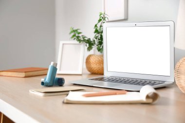 Çalışma masasında modern astım spreyleri, dizüstü bilgisayarlar, yakın plan.