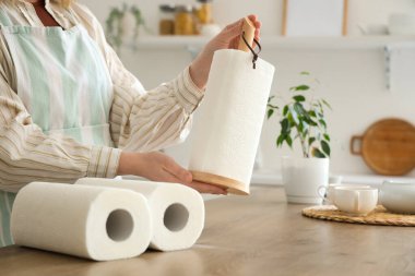 Mutfaktaki masanın yanında kağıt havluları olan genç bir kadın. Yakın plan.