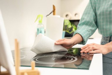 Mutfakta elektrikli soba temizleyen kağıt havluları olan genç bir kadın.