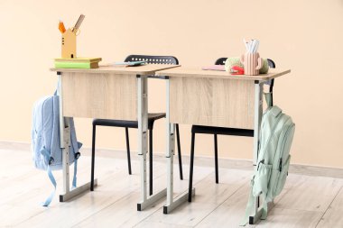 Bej arka planda sırt çantalı, kitaplı ve kırtasiyeli modern okul sıraları