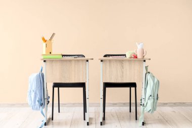 Bej arka planda sırt çantalı, kitaplı ve kırtasiyeli modern okul sıraları