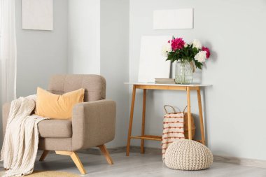 Gri koltuklu, masalı ve vazosunda güzel şakayıklar olan şık bir oturma odası.