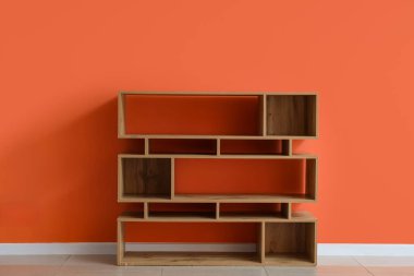 Turuncu duvarın yanındaki boş ahşap kitaplık.