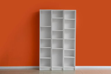 Turuncu duvarın yanındaki boş beyaz kitaplık