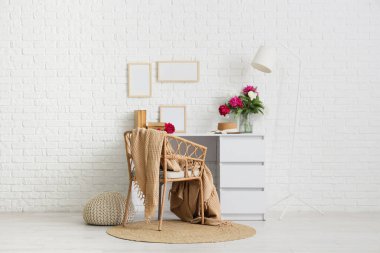 Sandalyesi, masası ve beyaz duvarın yanında güzel şakayıkları olan şık bir çalışma alanı.