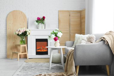 Gri kanepesi, şöminesi ve güzel şakayıkları olan şık bir oturma odası.