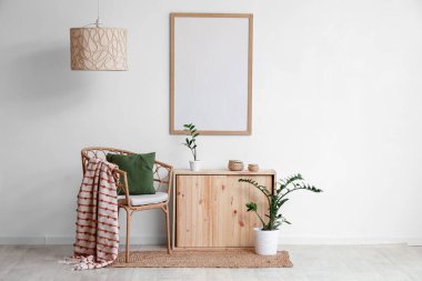 Yumuşak yastıklı rahat bir koltuk ve oturma odasındaki beyaz duvarın yanındaki ahşap çekmeceler.