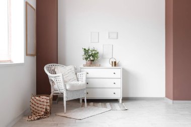 Rahat hasır koltuğu ve beyaz çekmeceleri olan şık bir oturma odası.