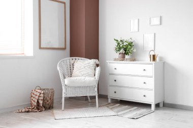 Rahat hasır koltuğu ve beyaz çekmeceleri olan şık bir oturma odası.