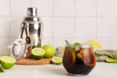 Bir bardak soğuk Küba Libre kokteyli. Nane ve limonlu beyaz masa.