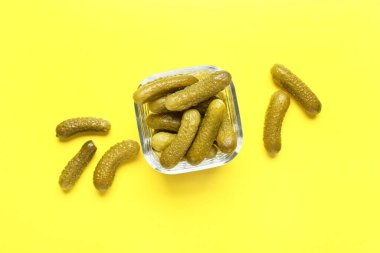 Sarı arka planda lezzetli salatalıklı cam kase.