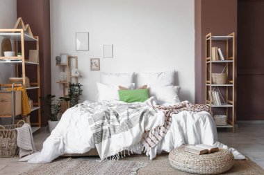 Konforlu yatağı, çiçekleri ve raf üniteleri olan hafif yatak odasının içi.