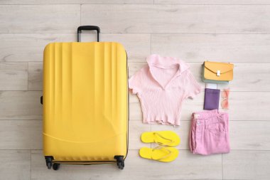 Bavul, yaz kıyafetleri ve yerde şık terlikler, üst manzara.