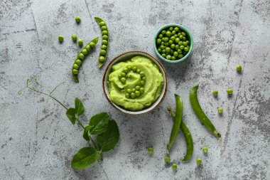 Gri arkaplanda püre yeşil bezelye ile kase