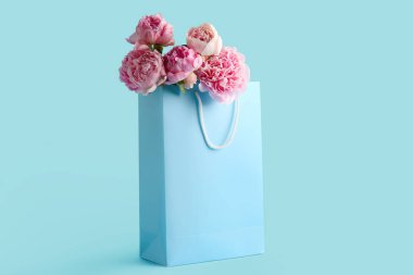 Mavi arka planda pembe şakayık çiçekleri olan bir alışveriş çantası.