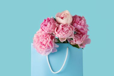 Mavi arka planda pembe şakayık çiçekleri olan bir alışveriş çantası.