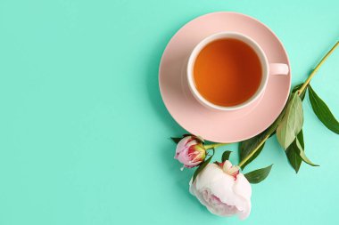 Güzel şakayık çiçekleri ve turkuaz arka planda bir fincan sıcak çay.