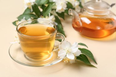 Cam bardak ve çaydanlık sıcak yasemin çayı bej arka planda çiçekler, yakın plan