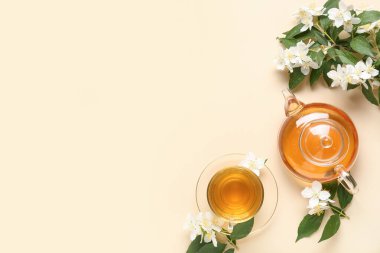 Cam bardak ve çaydanlık bej arka planda çiçekli sıcak yasemin çayı.