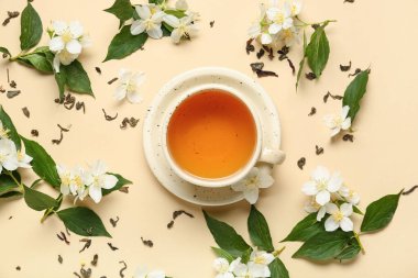 Bej arkaplanda çiçekler olan bir fincan sıcak yasemin çayı.