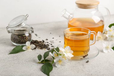 Cam bardak ve çaydanlık beyaz arka planda kuru yapraklı sıcak yasemin çayı.