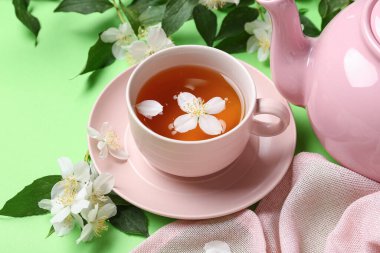 Yeşil arka planda çiçekli sıcak yasemin çayı, yakın plan.