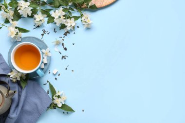 Çiçekli sıcak yasemin çayı ve mavi arka planda kuru yapraklar.