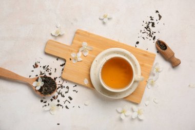 Bir fincan sıcak yasemin çayı, çiçekler ve beyaz arka planda kuru yapraklar.