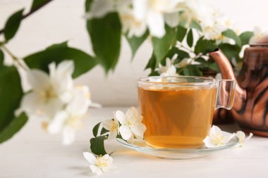 Beyaz arka planda çiçekli bir bardak sıcak yasemin çayı.