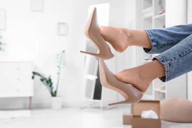 Yeni bej renkli yüksek topuklu ayakkabılı genç bayan evde.