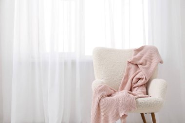 Koltuk ve ekose kumaş. Odada ışık perdesi var.