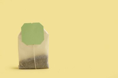 Sarı arkaplanda çay poşeti, yakın plan.