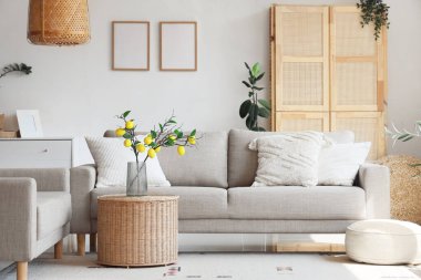 Oturma odasının içinde rahat koltuklar ve beyaz duvarın yanındaki masa.