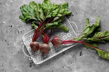Gri grunge arka planında taze pancar kökleri olan tepsi