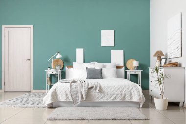 Yatak odasının iç kısımlarında yeşil duvarın yanında büyük rahat yatak ve komodinleri var.